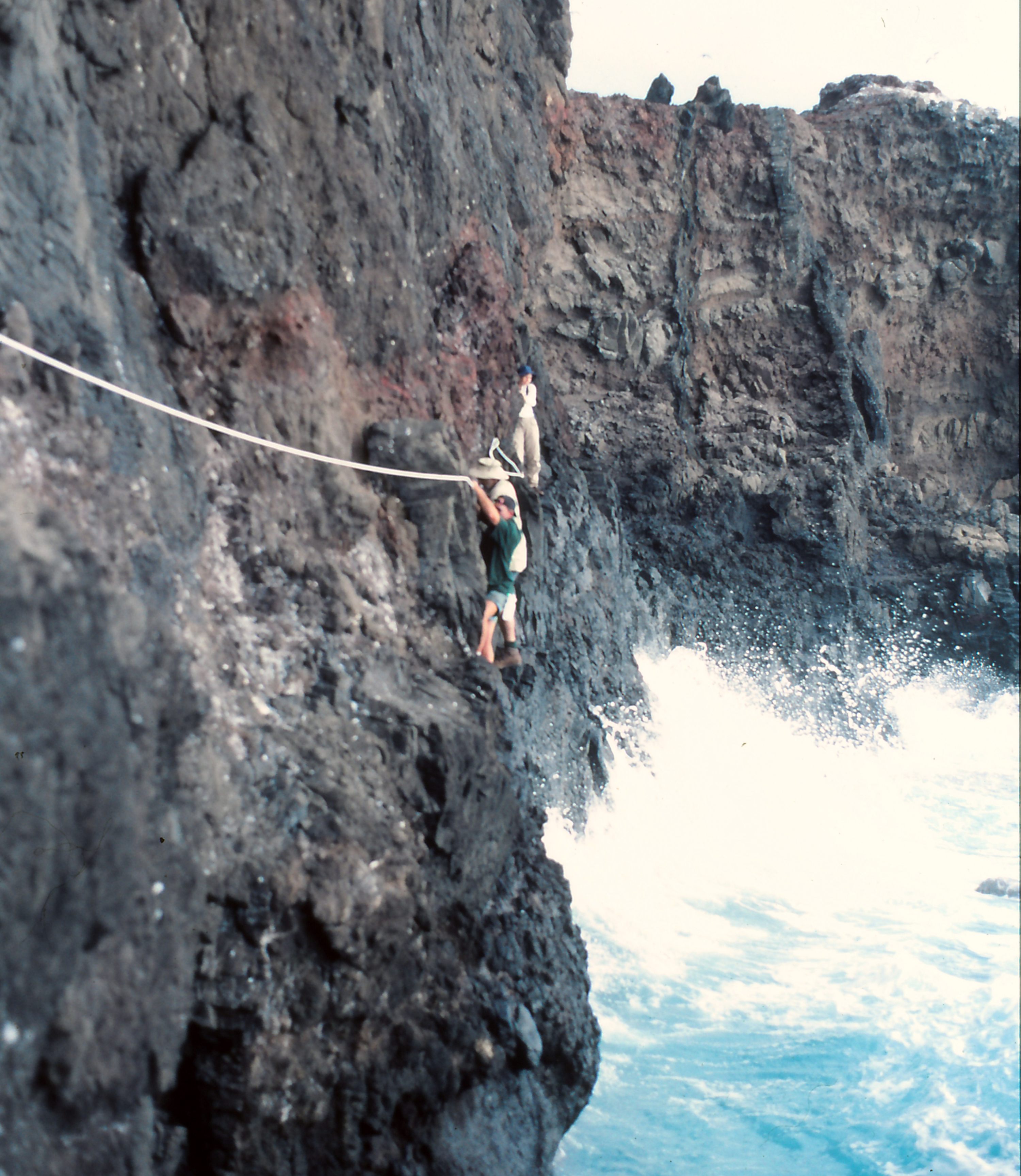 Členové výpravy Davida Priddela traverzují před začátkem výstupu na Ballovu pyramidu po tenké římse těsně nad vlnami. Foto: Nicholas Carlile. Zdroj: Return of the Phasmid, R. Wilkinson